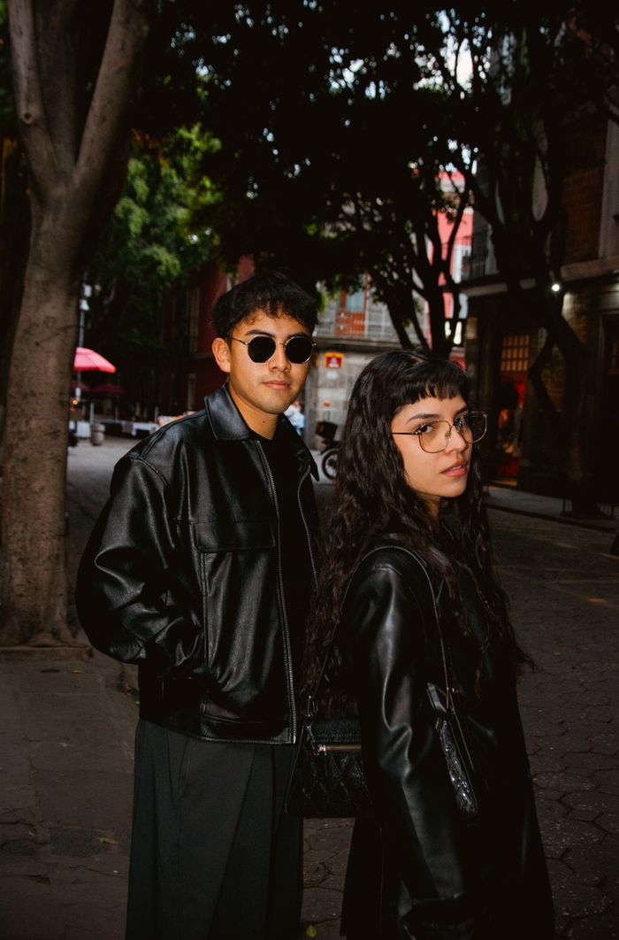 About Young couple in black jackets strolling through a vibrant city street.